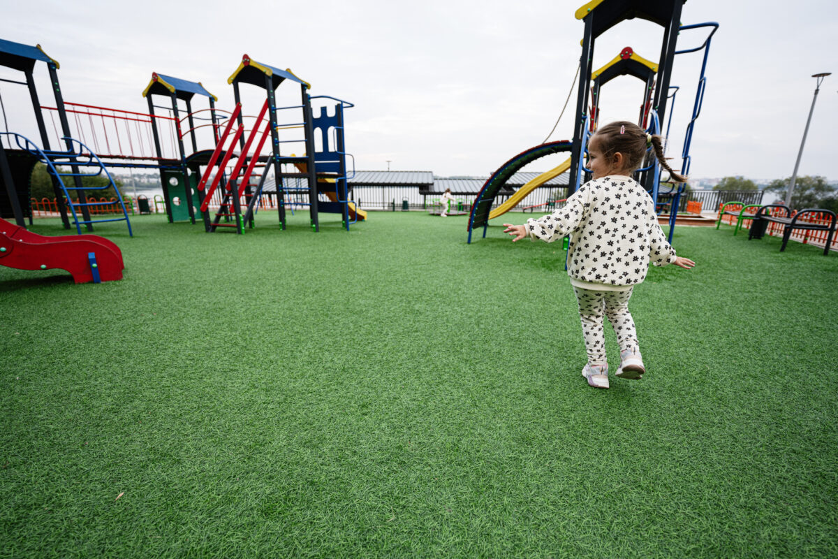 A young child happily runs across a vibrant playground with slides and climbing frames, embodying joy and childhood freedom.
